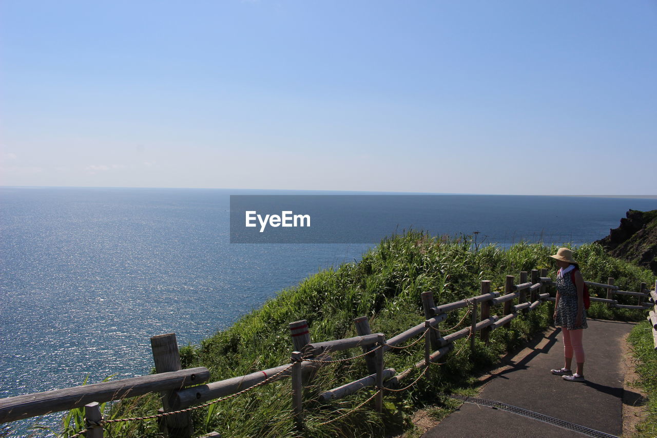 Woman looking at sea while standing on walkway