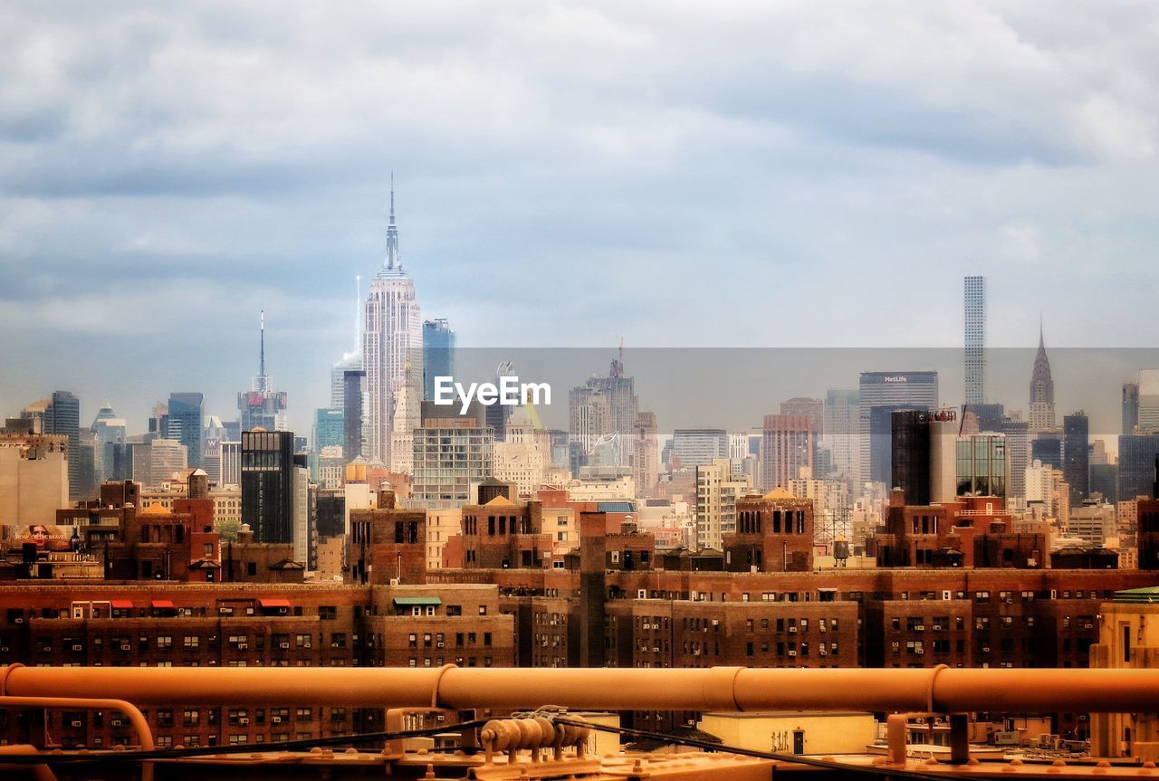 Buildings in city against cloudy sky