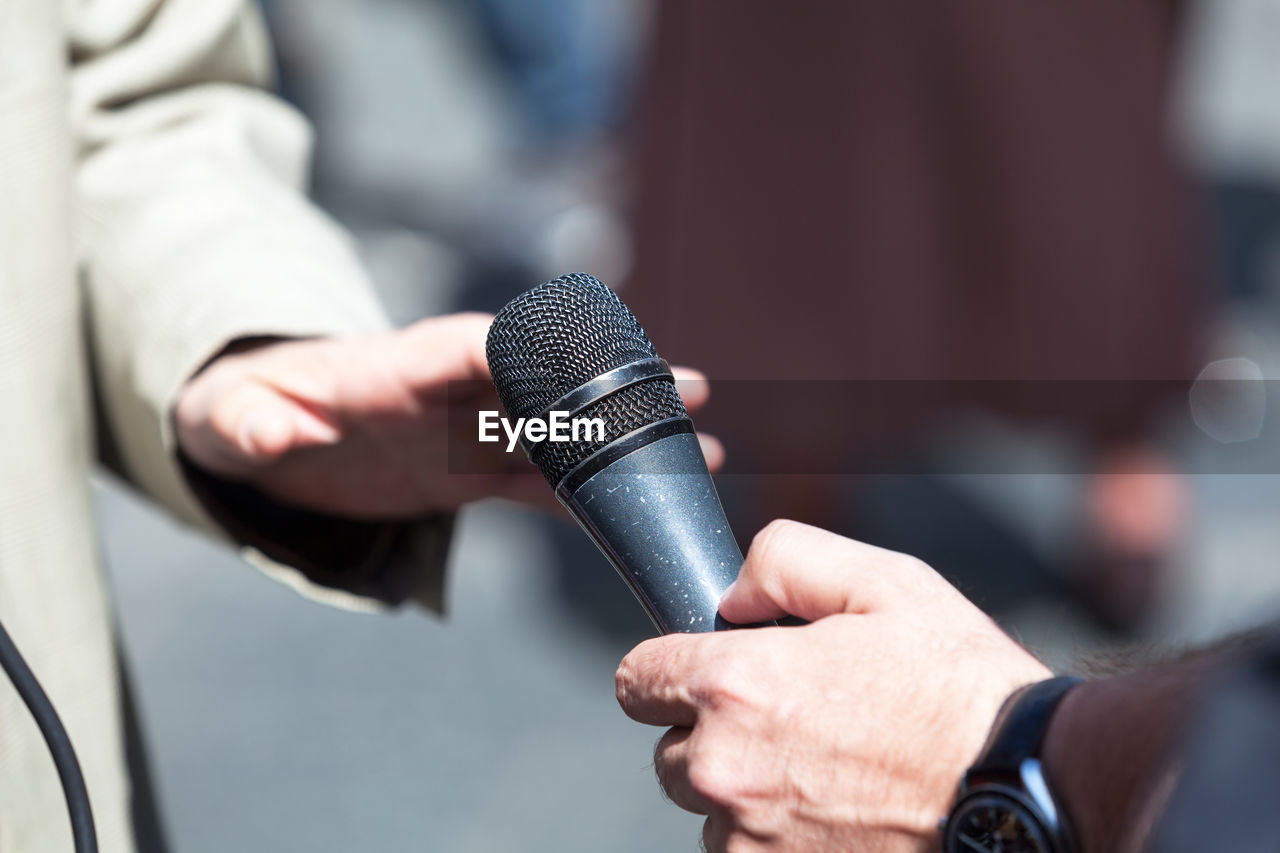 Cropped hand of male journalist interviewing businessman