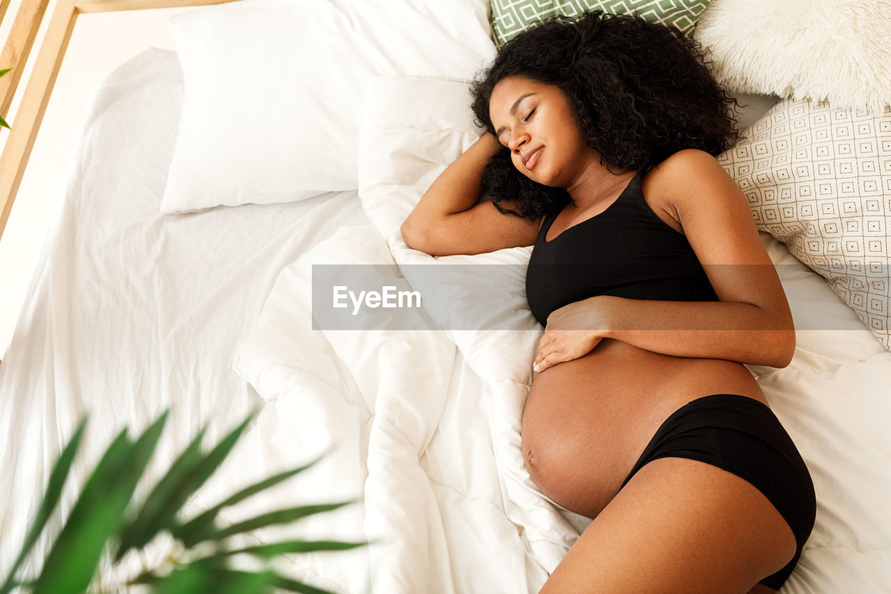 Pregnant woman sleeping on bed