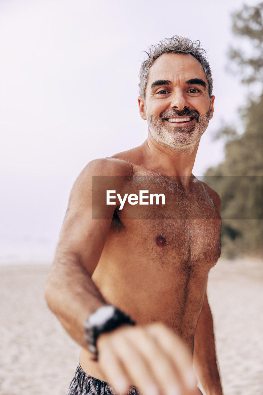 Portrait of smiling shirtless man spending vacation at beach
