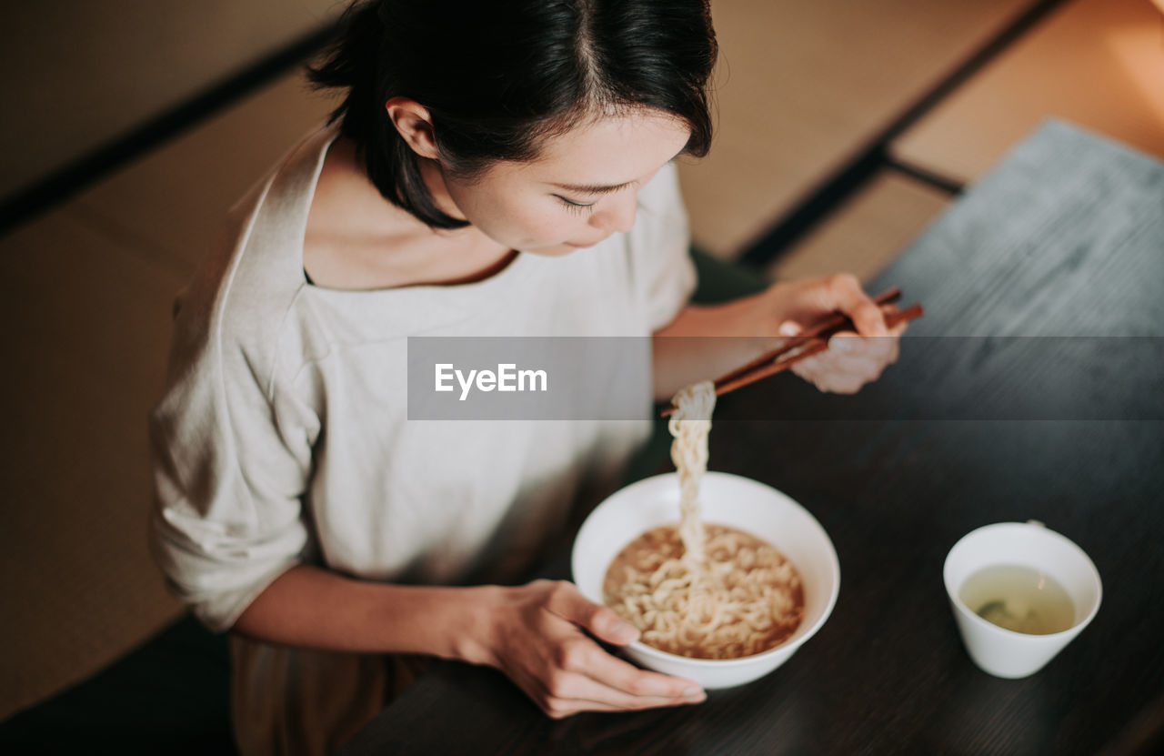 High angle view of woman eating food sitting at home