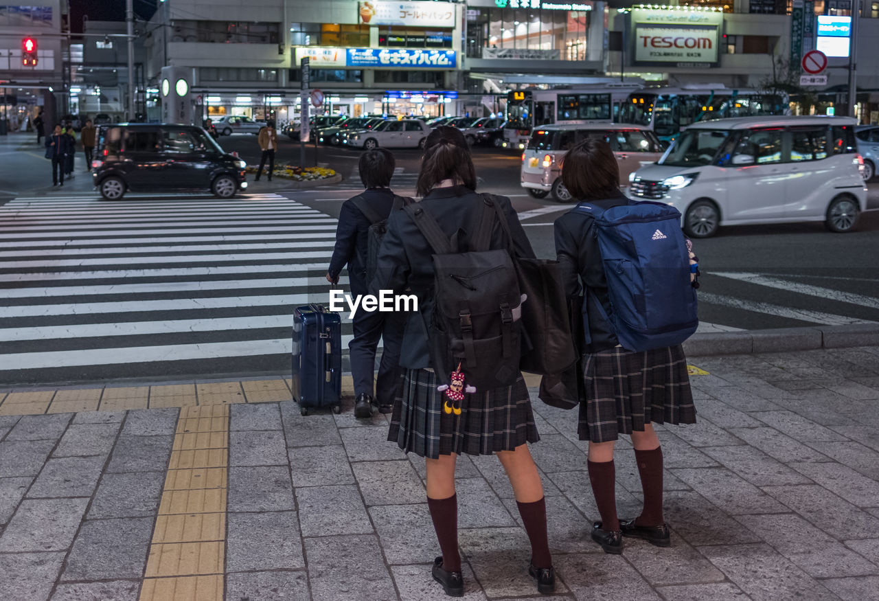 REAR VIEW OF PEOPLE WALKING ON CITY STREET