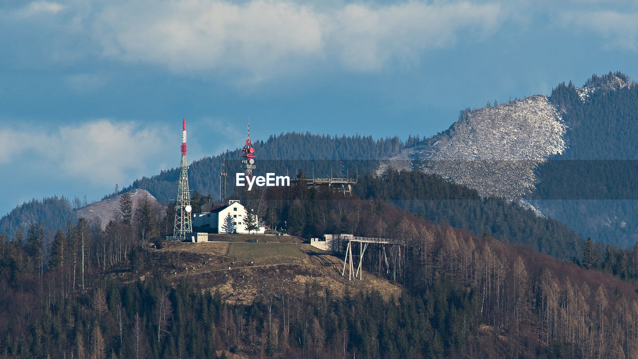 PANORAMIC SHOT OF BUILDING BY MOUNTAINS AGAINST SKY