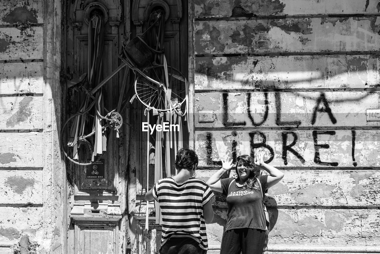 REAR VIEW OF PEOPLE STANDING BY WALL