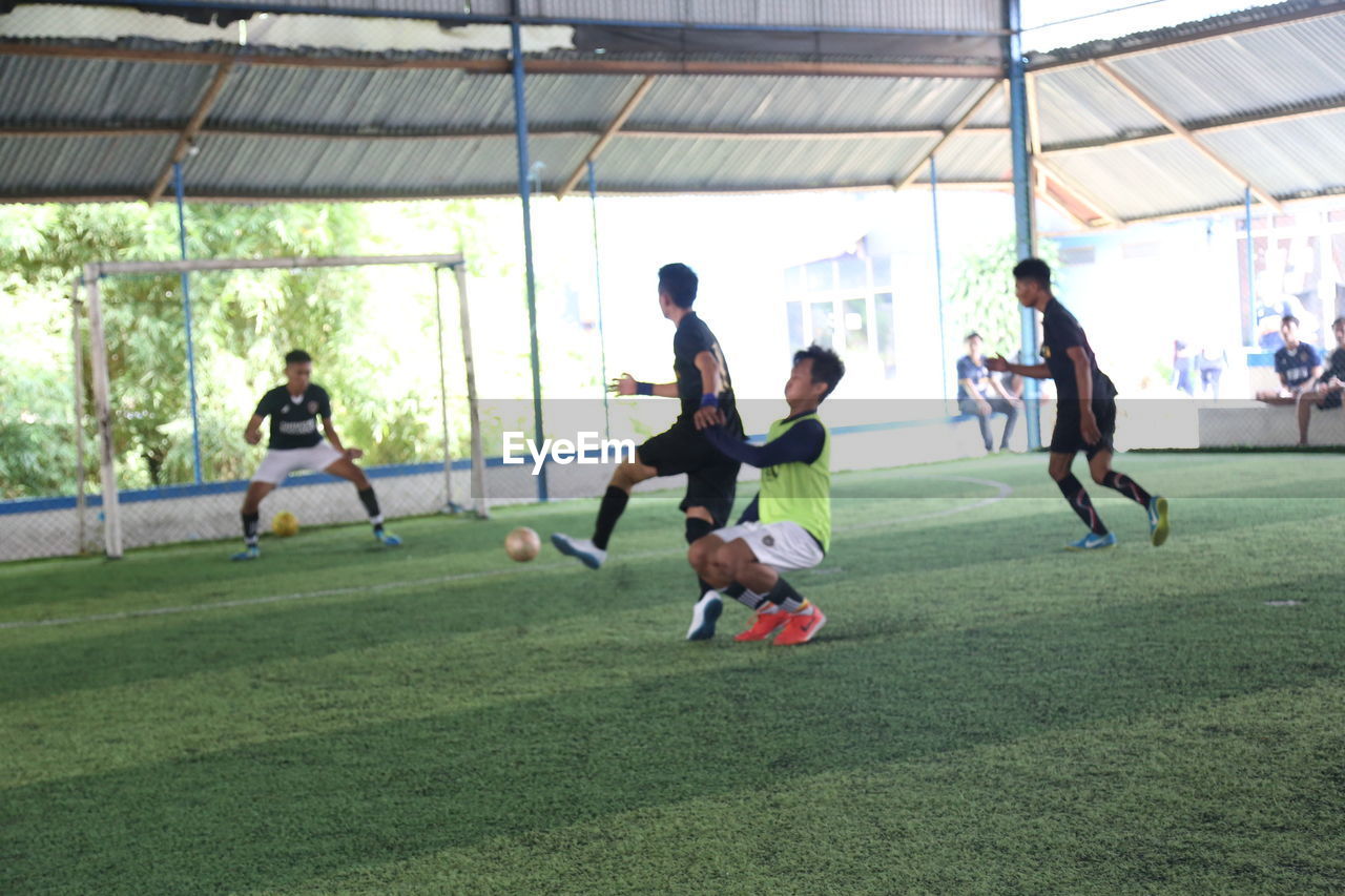 GROUP OF PEOPLE PLAYING SOCCER BALL ON FIELD