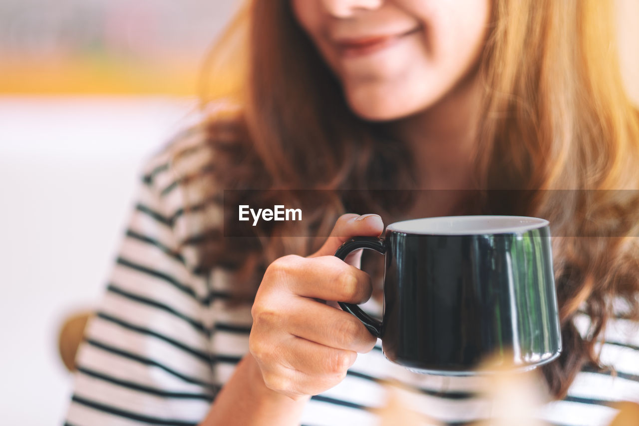 Midsection of woman having coffee at cafe