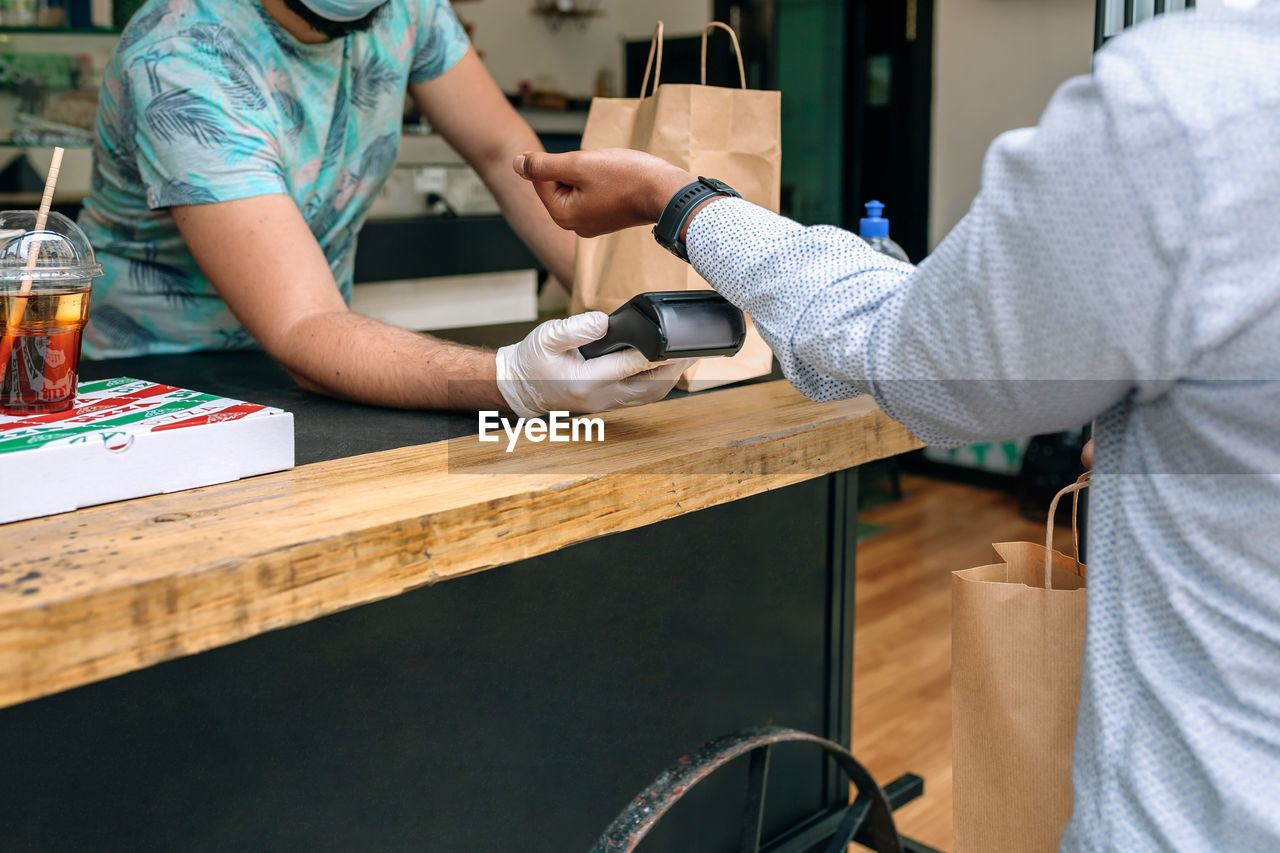 Midsection of couple holding hands while sitting on table