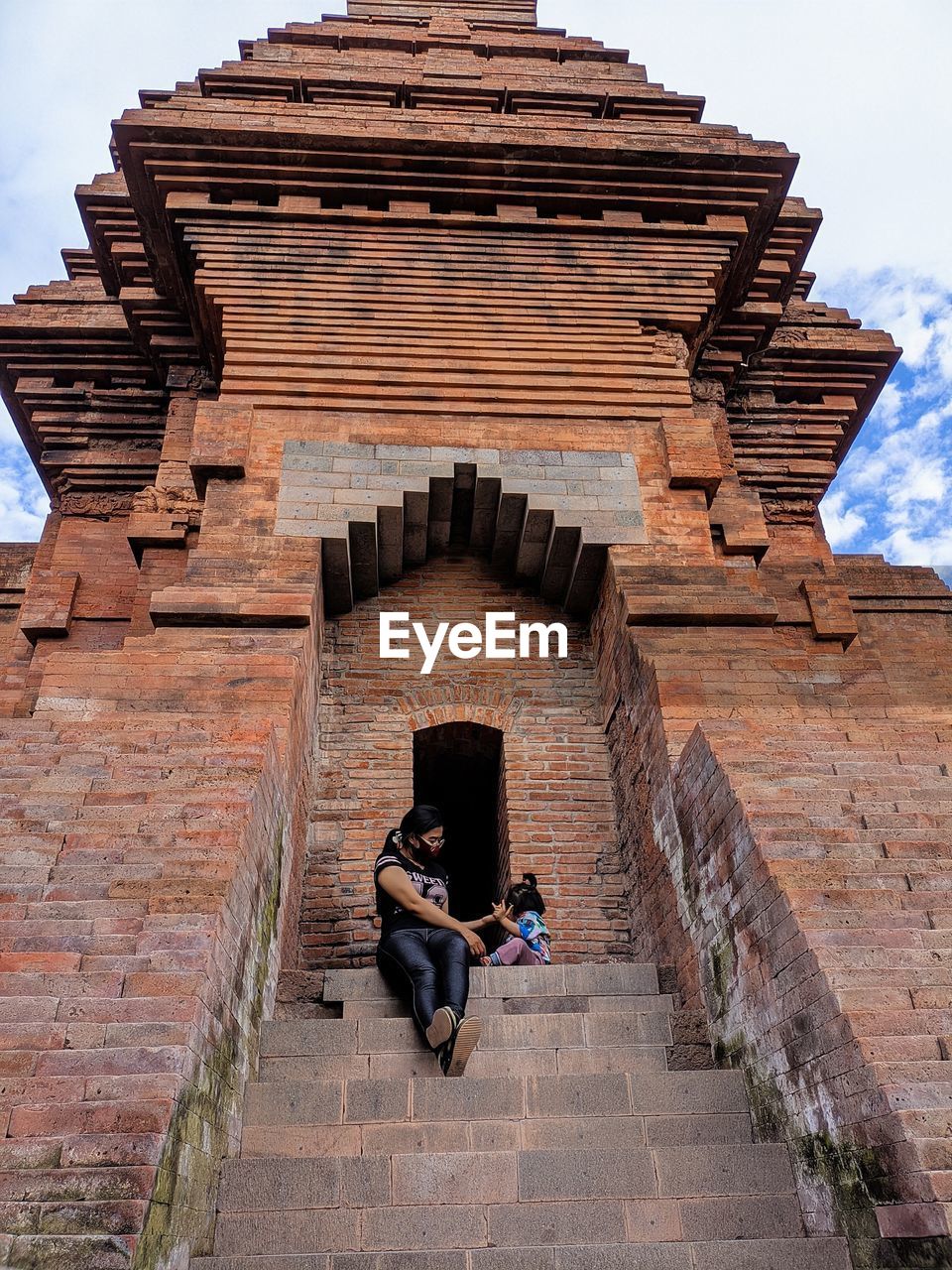 architecture, built structure, history, staircase, travel destinations, the past, one person, travel, full length, temple, building exterior, religion, ancient history, temple - building, tourism, adult, sitting, nature, ancient, brick, leisure activity, lifestyles, outdoors, belief, sky, day, steps and staircases, building, men, relaxation, spirituality, tourist, vacation, person, rock, activity, landmark, wall