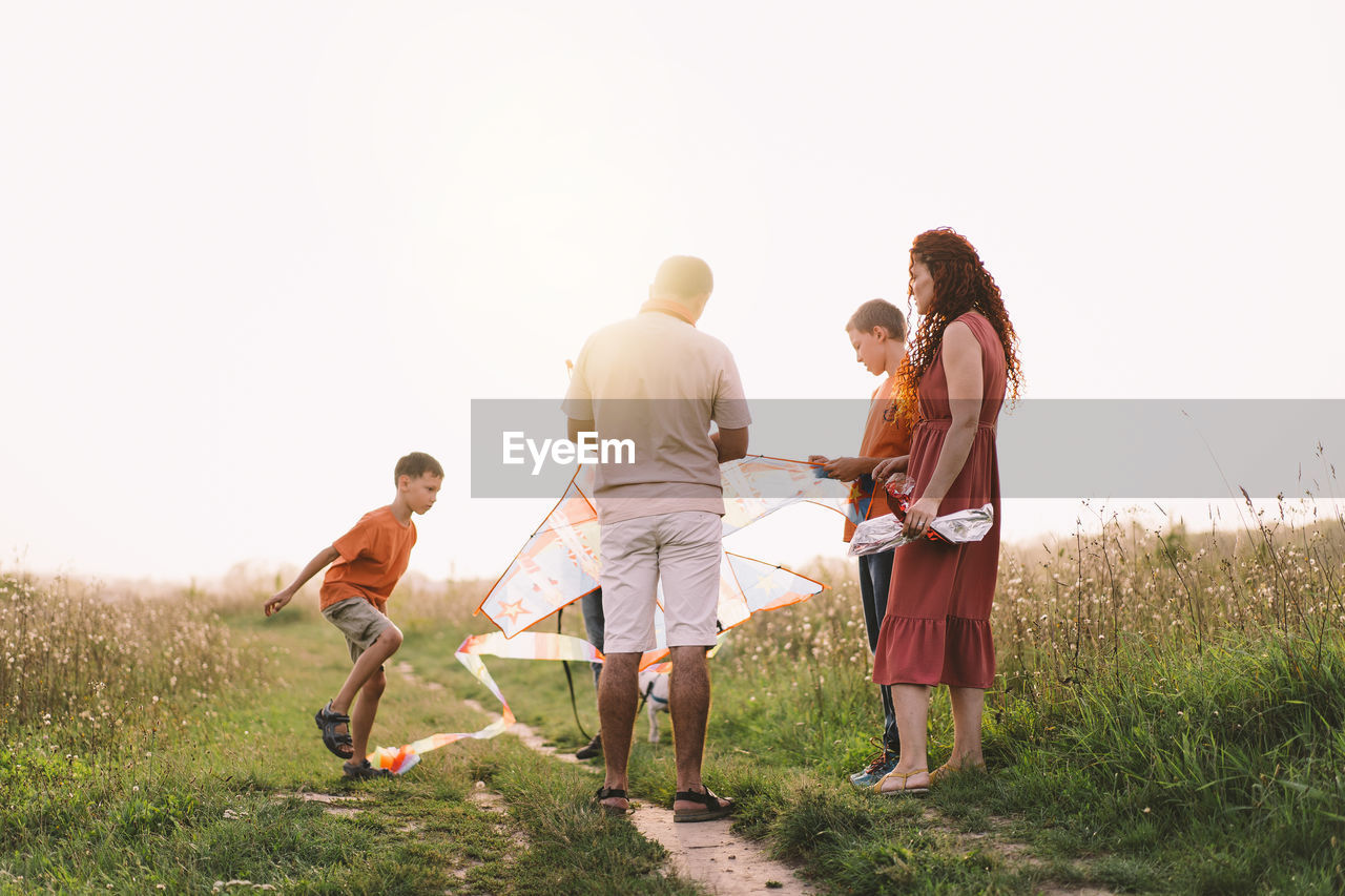 Happy family and children run on meadow with a kite in the summer on the nature.