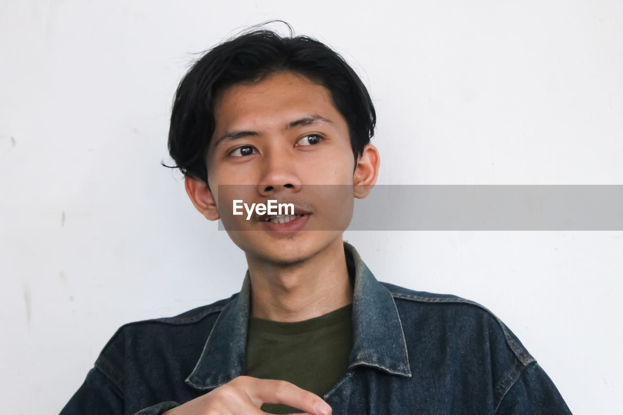 Portrait of young man standing against wall