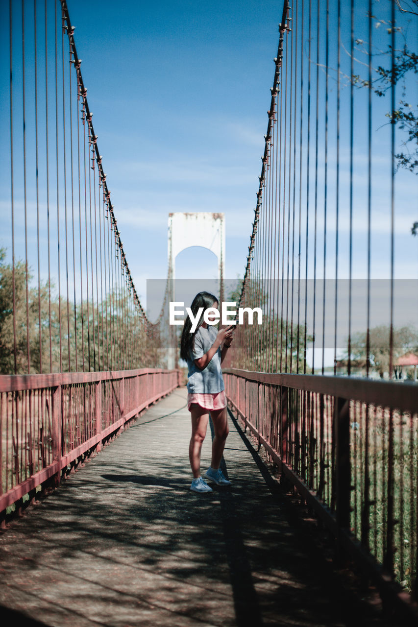 Full length of young woman standing on footbridge