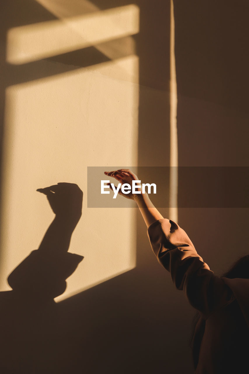 Cropped hand of woman gesturing against wall