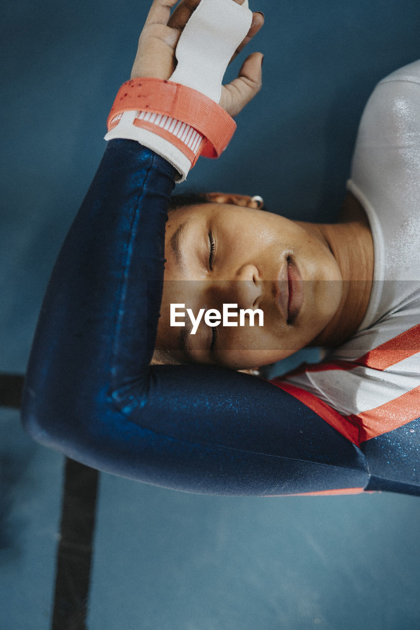 Directly above shot of female athlete with eyes closed resting on floor