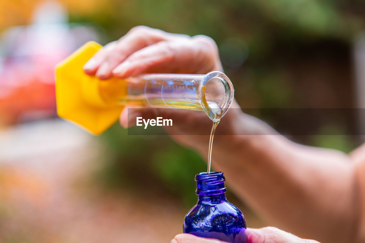 CLOSE-UP OF WOMAN HAND HOLDING BOTTLE WITH LIGHT