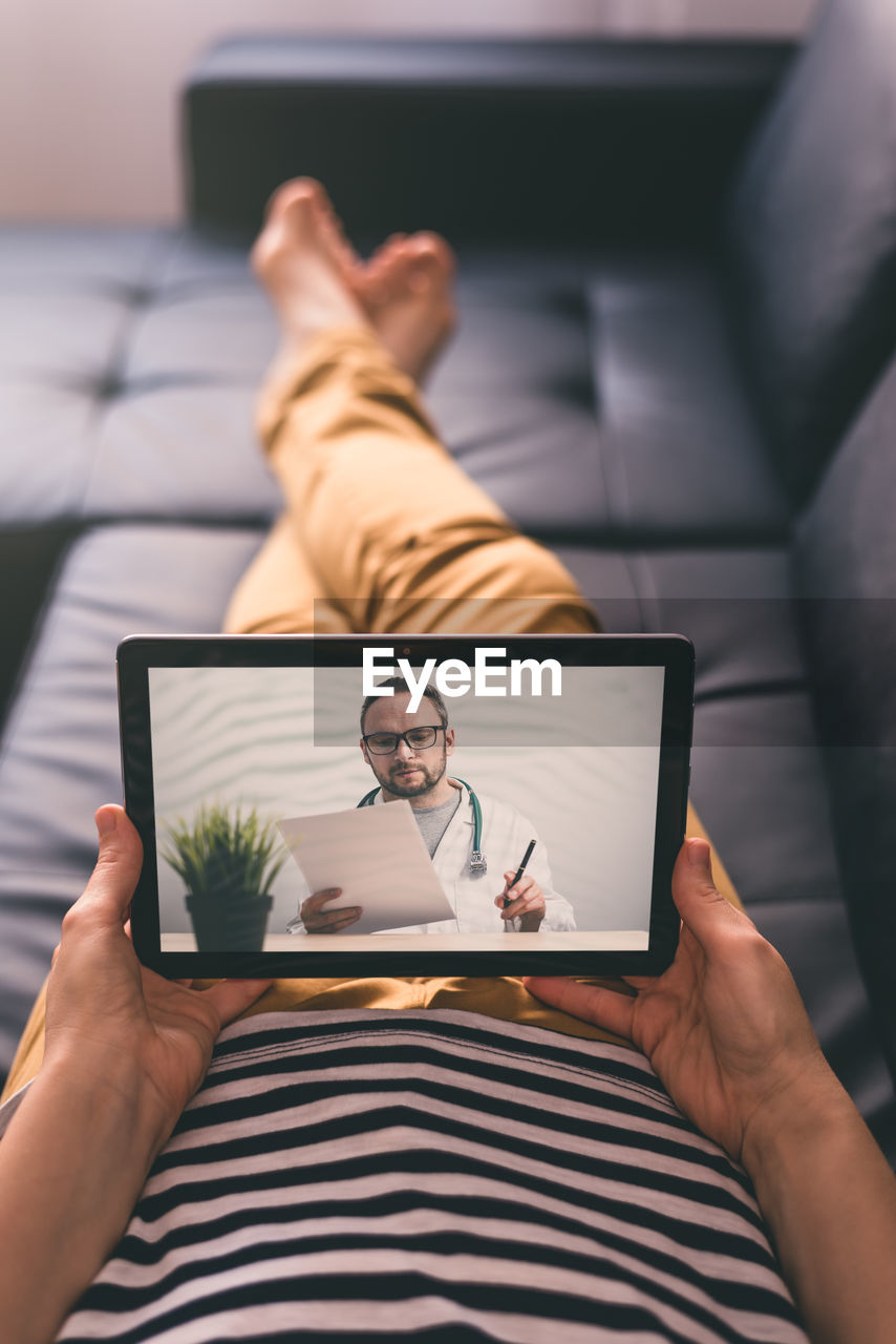 Woman lying on a sofa and talking with a doctor online using digital tablet. telemedicine concept.