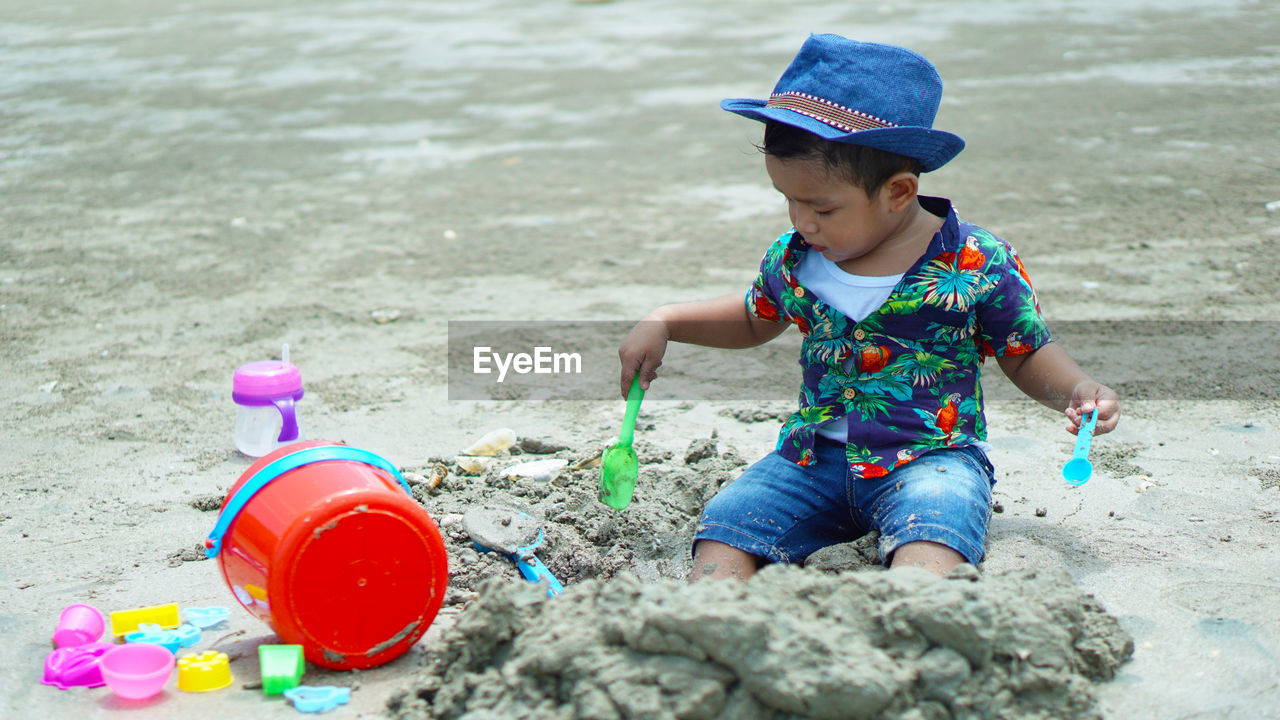 Boy playing with toys on sand at beach