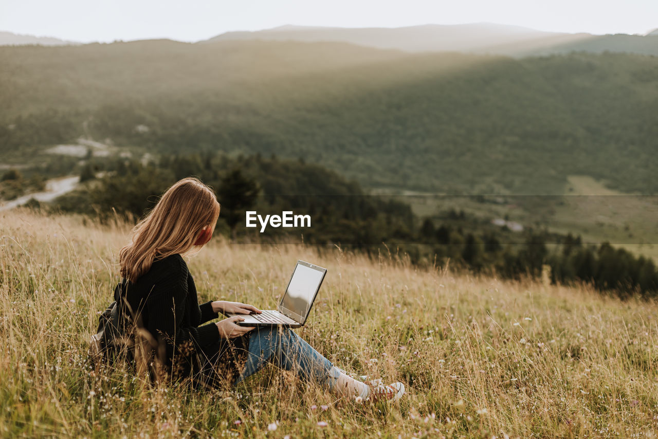 Woman with mask working on laptop in remote location