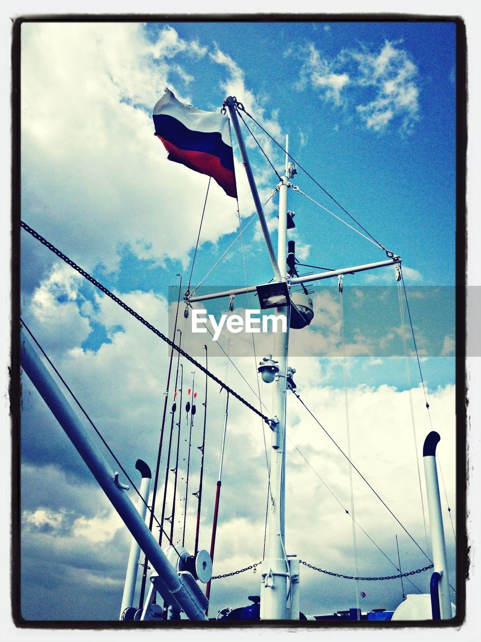 Low angle view of boat mast against cloudy sky