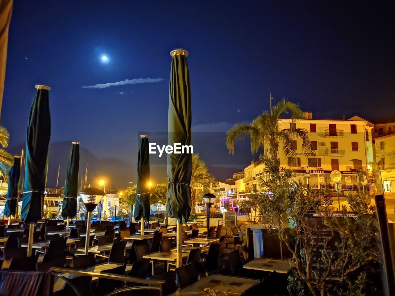 Illuminated harbor by buildings against sky at night