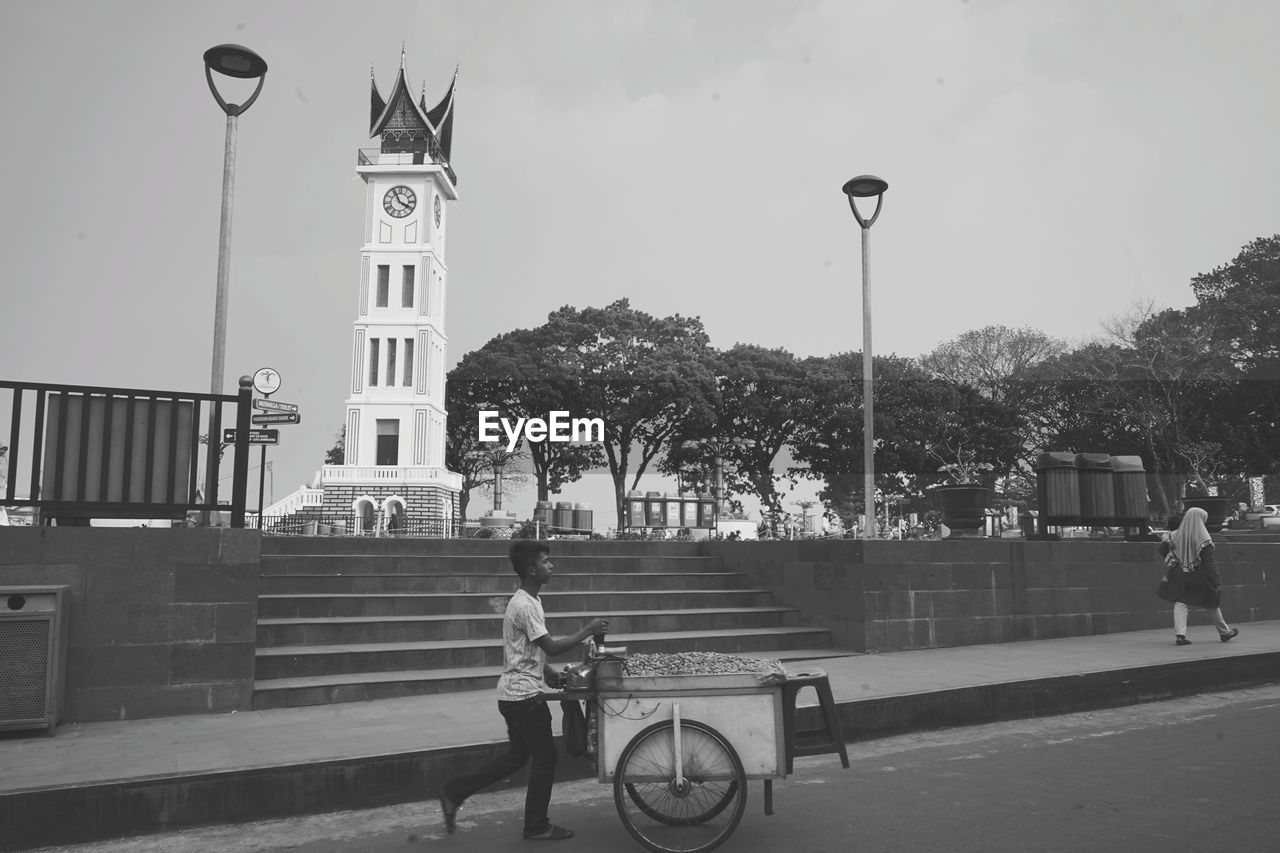 MAN WALKING ON STREET AGAINST BUILDING