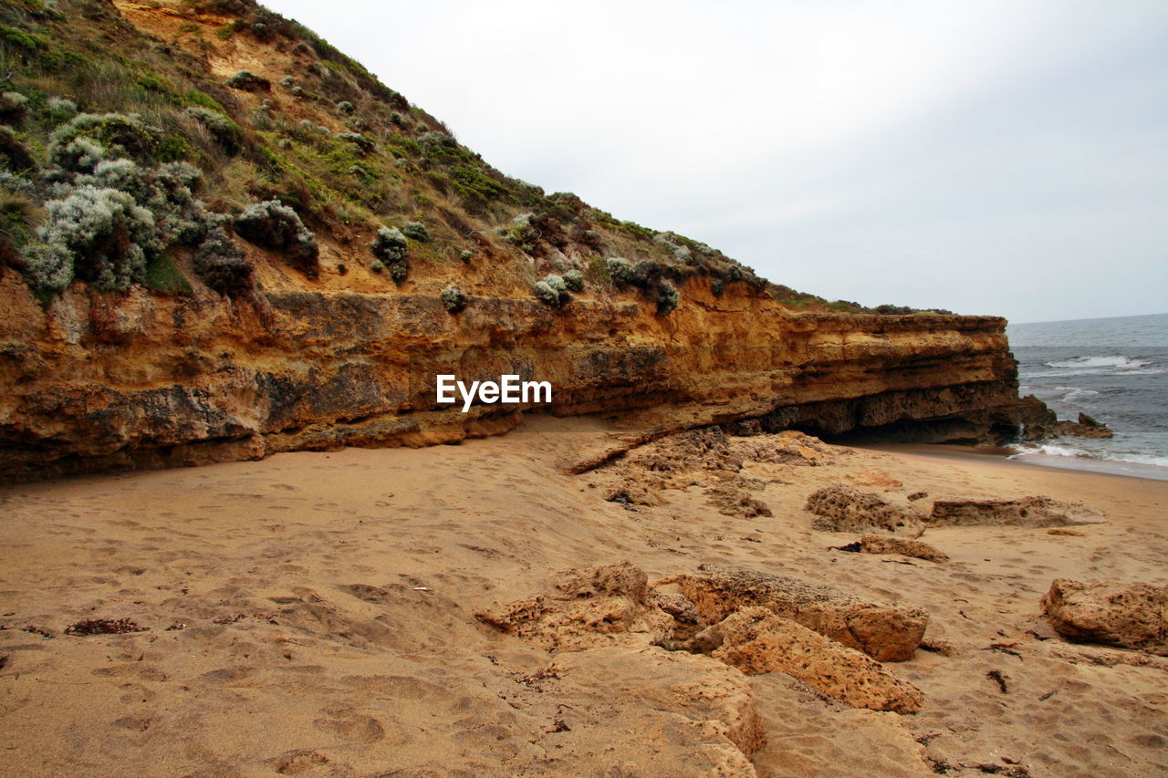 Cliff by sea against sky