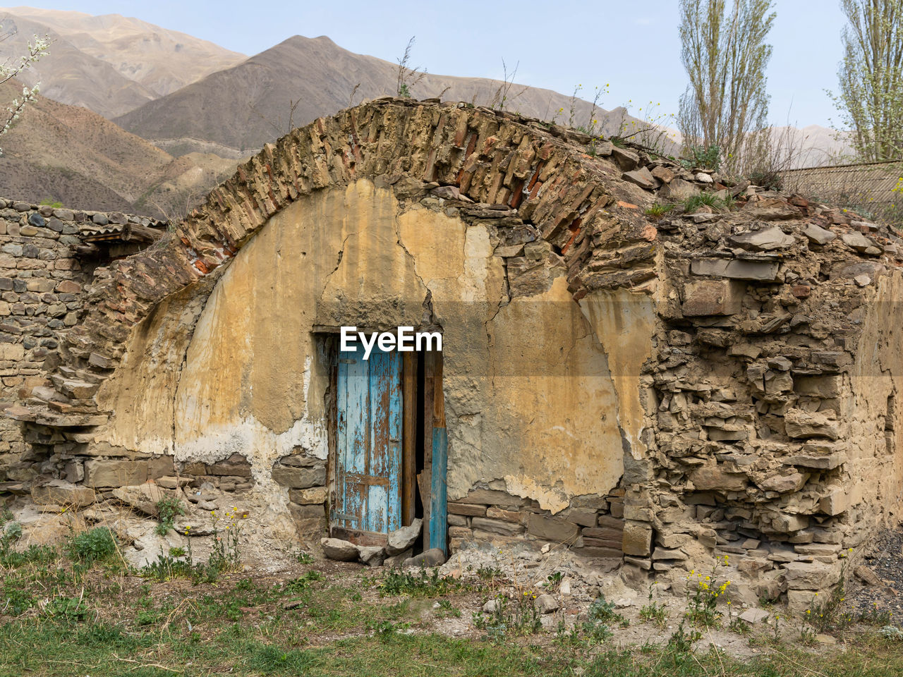 EXTERIOR OF OLD ABANDONED HOUSE AND MOUNTAINS