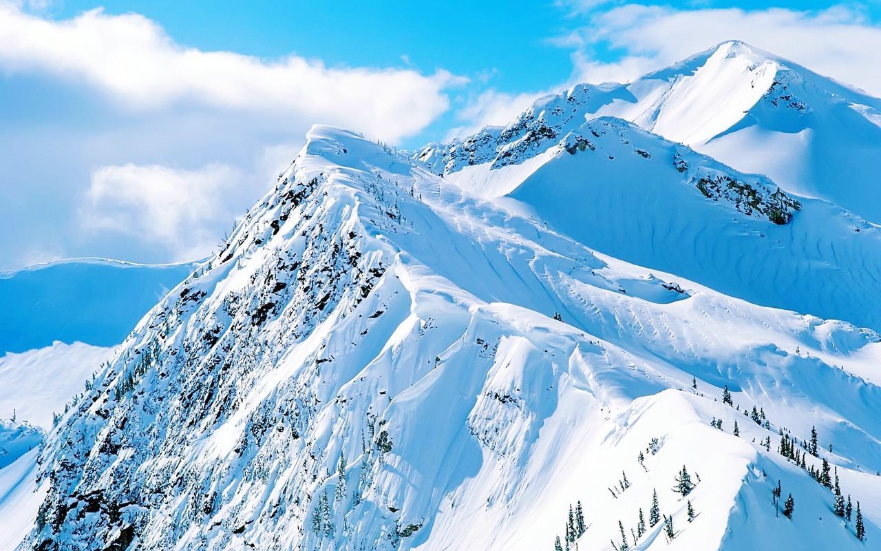 Scenic view of snowcapped mountains against cloudy sky