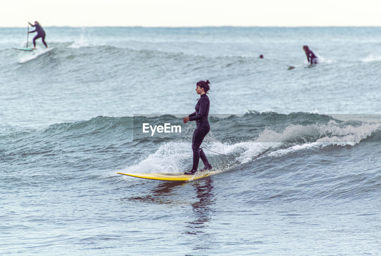 MAN SURFING ON SEA AGAINST PEOPLE