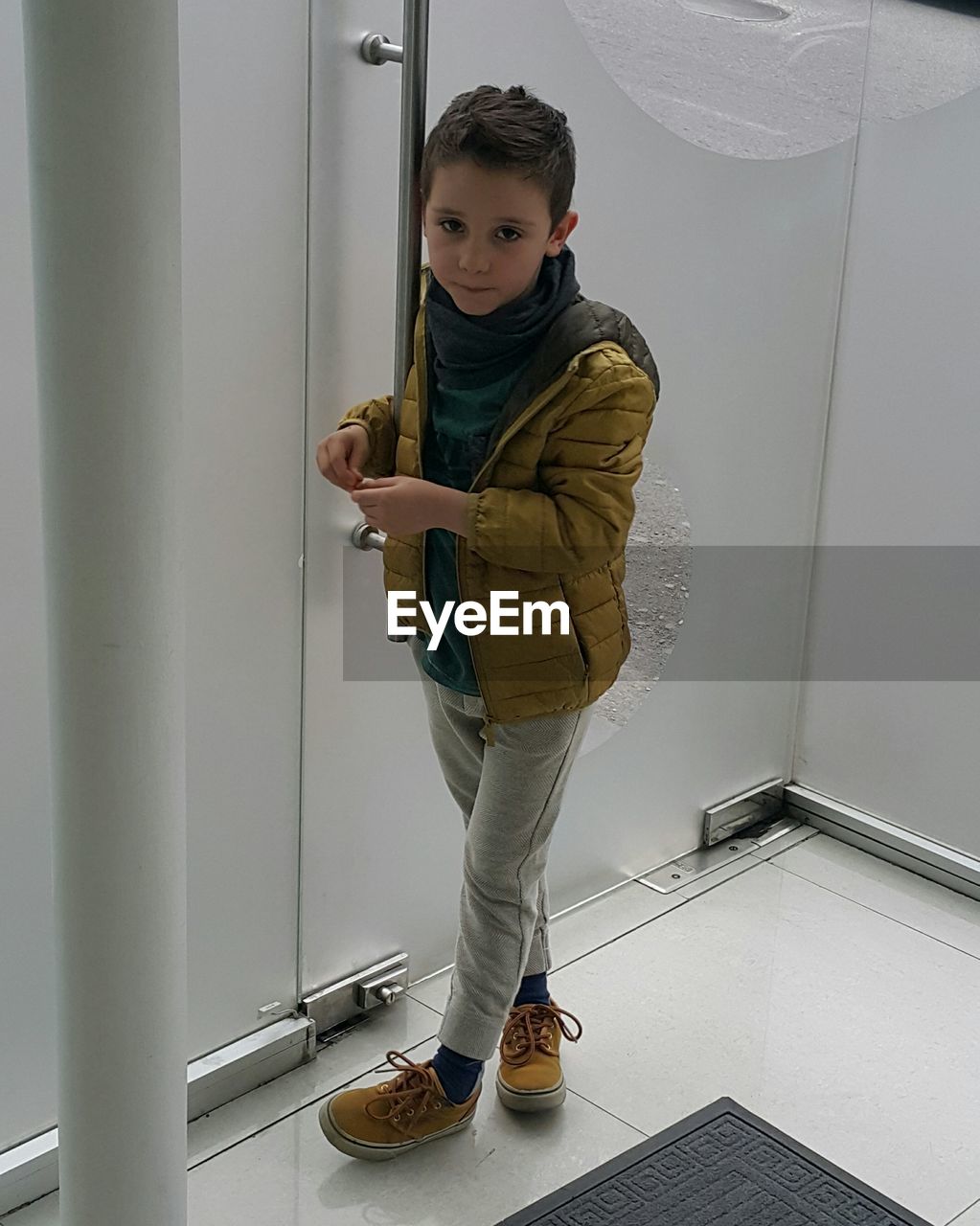 Portrait of cute boy standing by wall in room