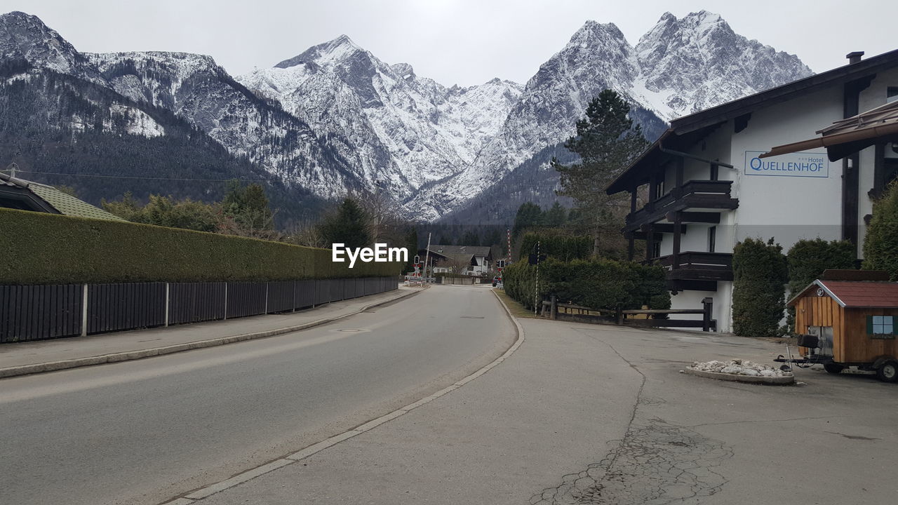 ROAD AMIDST HOUSES AGAINST MOUNTAINS