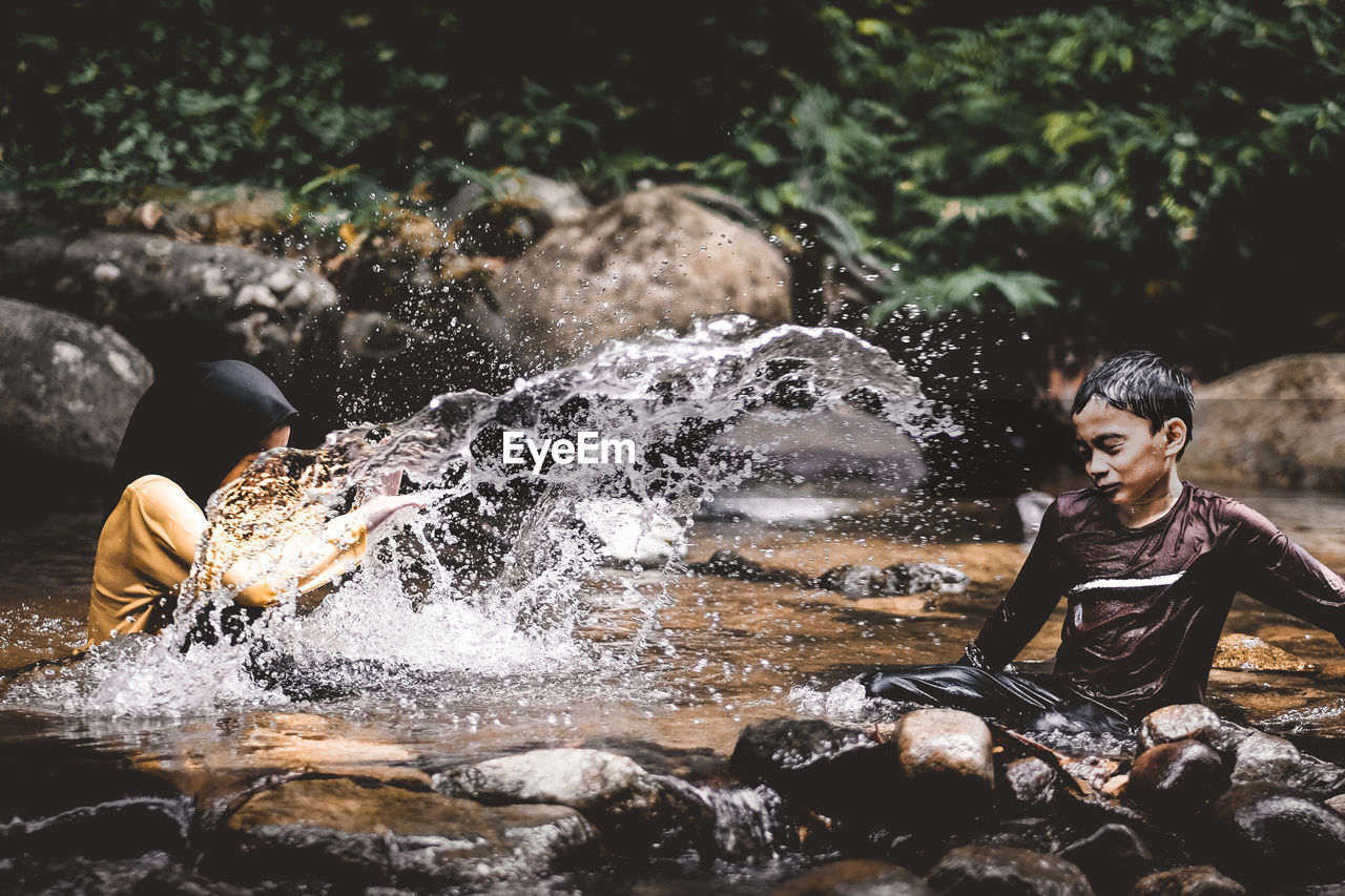 Cheerful siblings playing in river