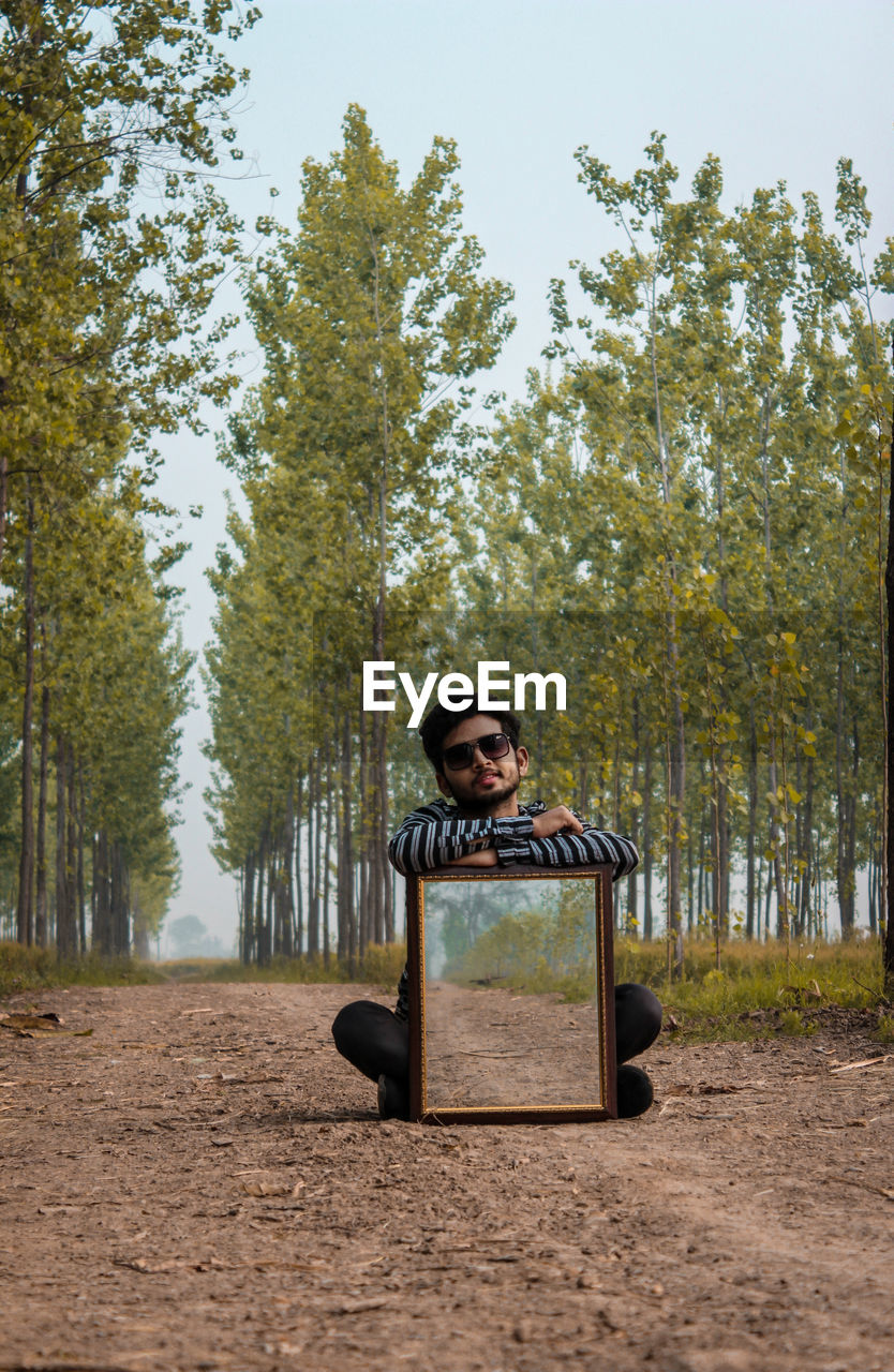 Portrait of boy sitting on seat against trees