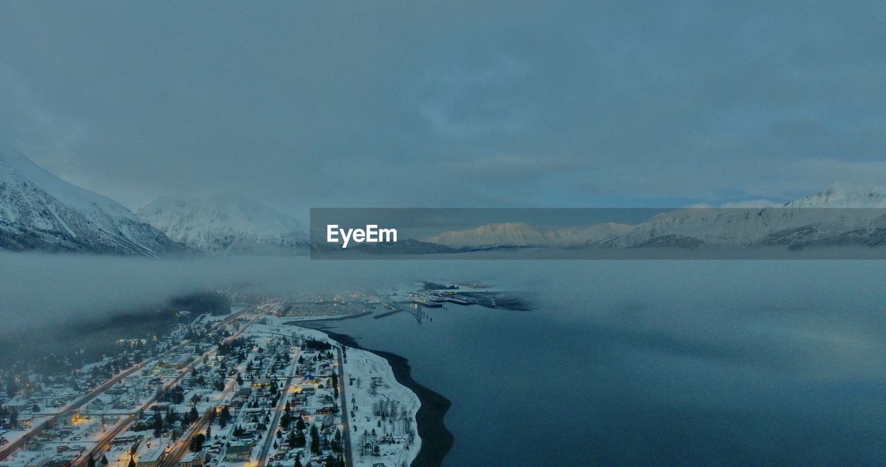 Aerial view of lake by snowcapped mountains against sky