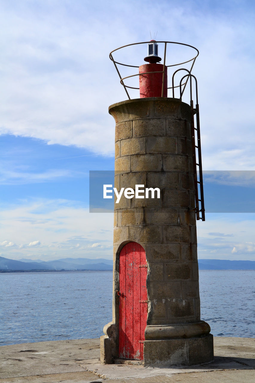 Lighthouse by sea against sky