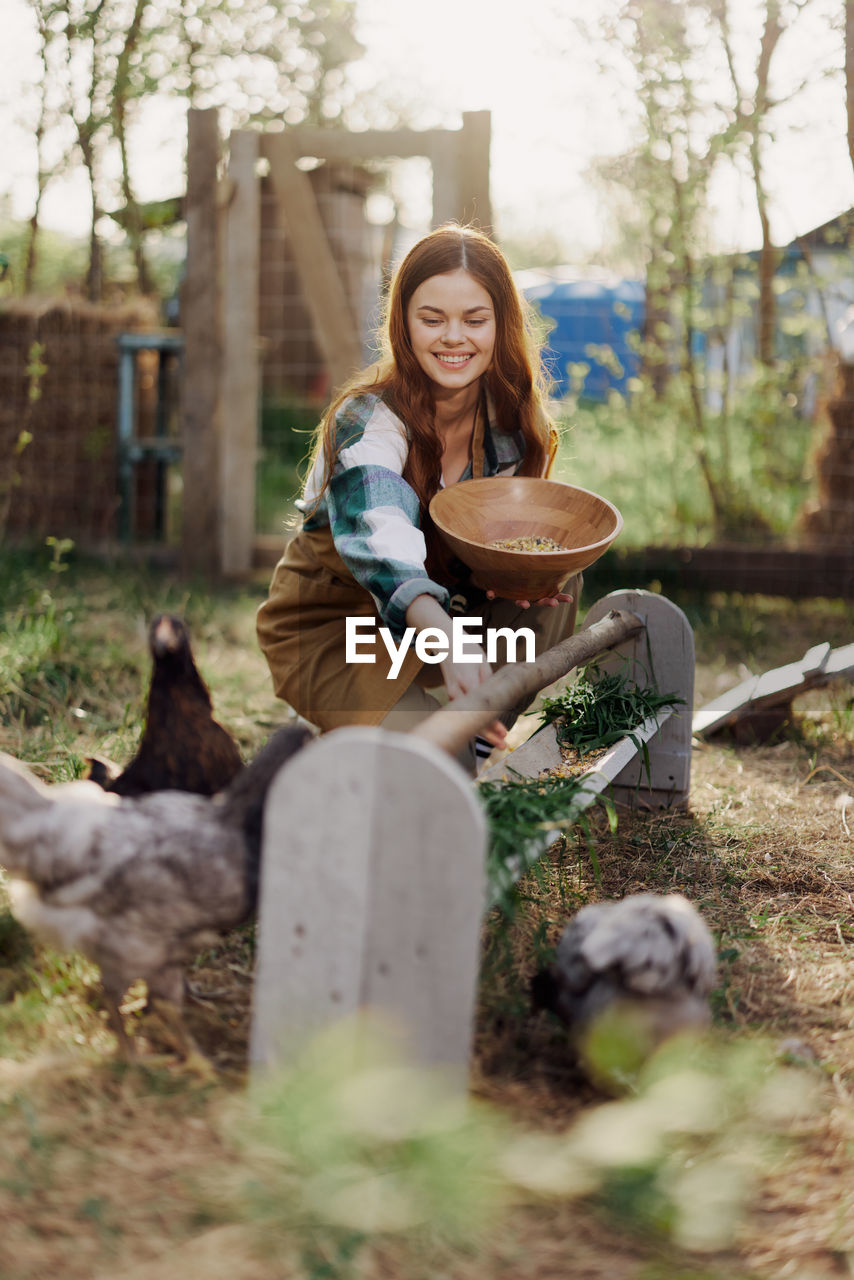 Young woman feeding chickens at farm