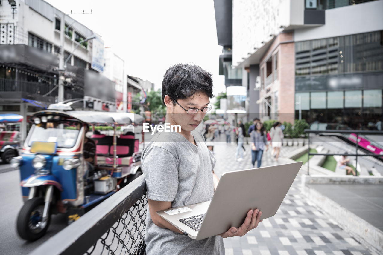 Man using laptop while standing in city