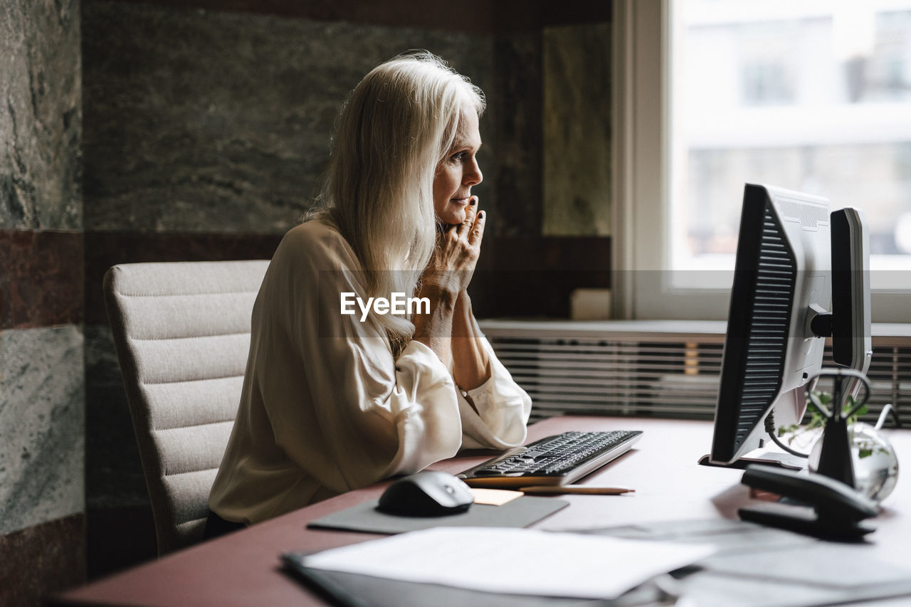 Female lawyer with long white hair staring at computer in office