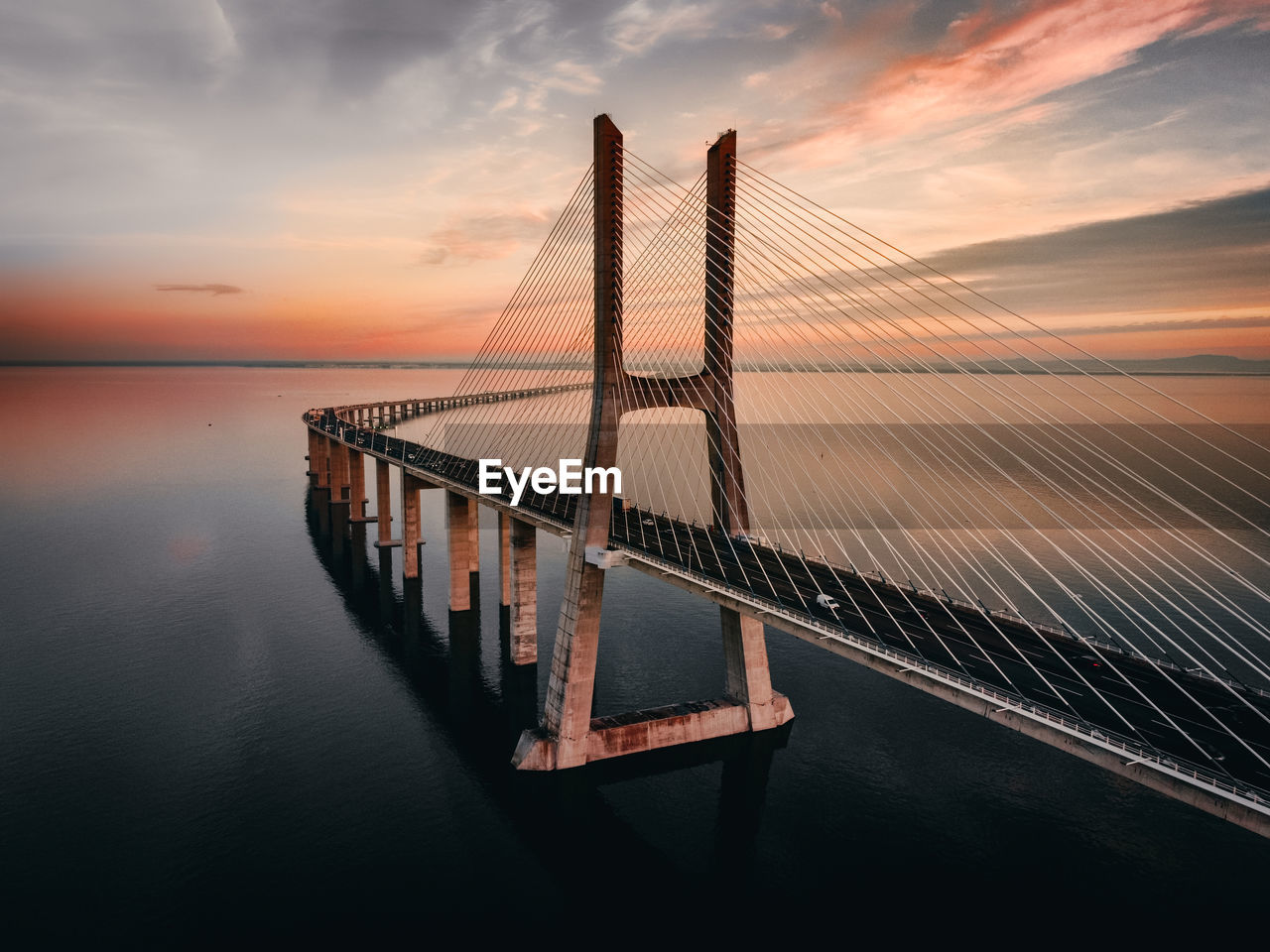 Bridge over calm sea against sky during sunset