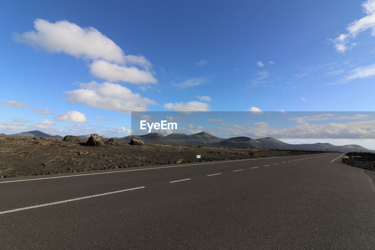 Road by mountains against sky