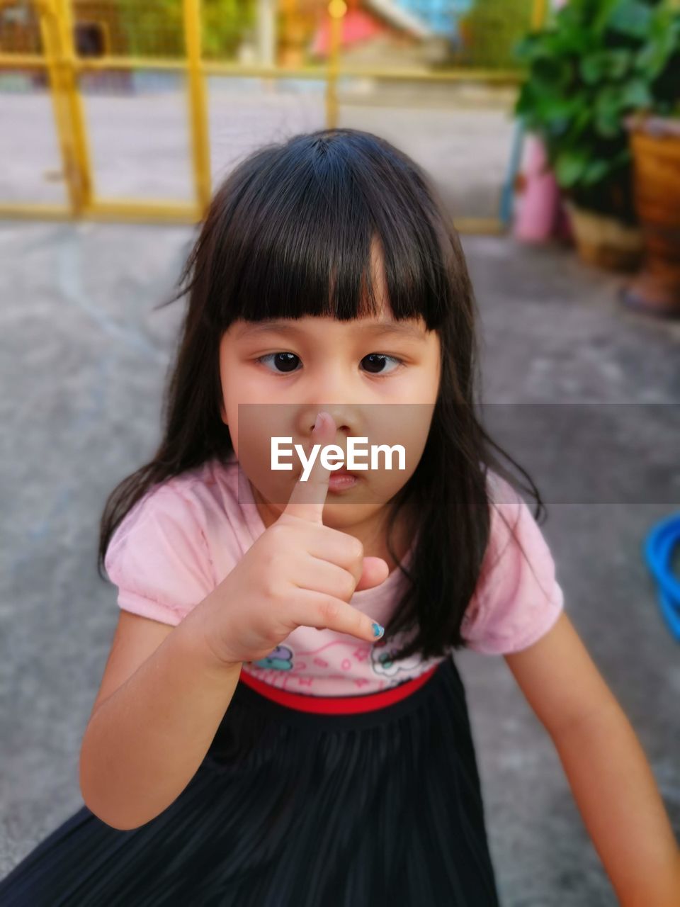 Portrait of cute girl with finger on lips standing on land