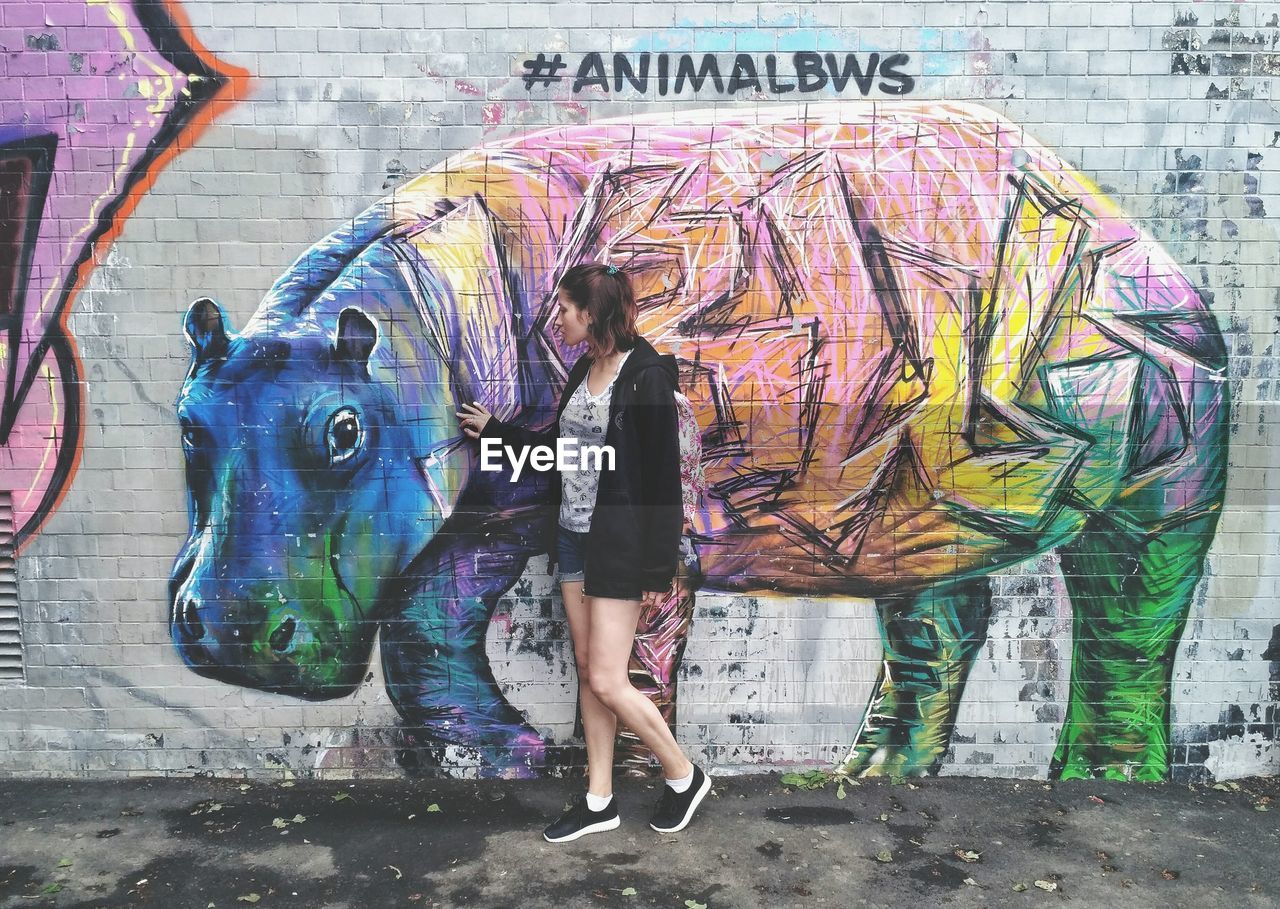 WOMAN STANDING ON GRAFFITI WALL