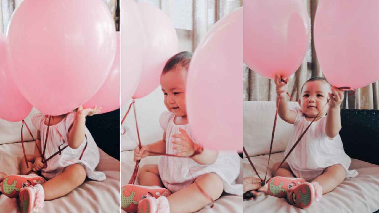 HAPPY GIRL PLAYING WITH BALLOONS AT HOME