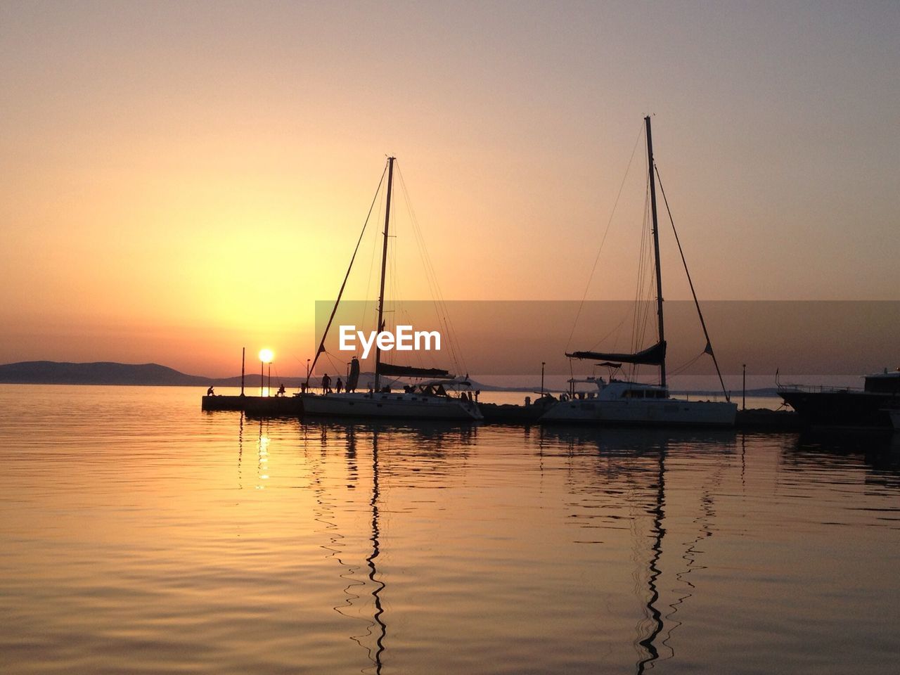 Side view of boats in sea at sunset