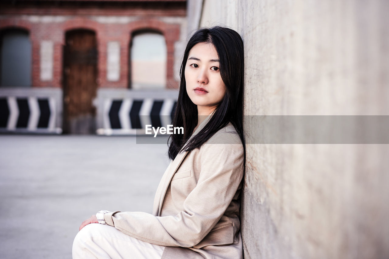 Portrait of confident chinese woman in city leaning on wall