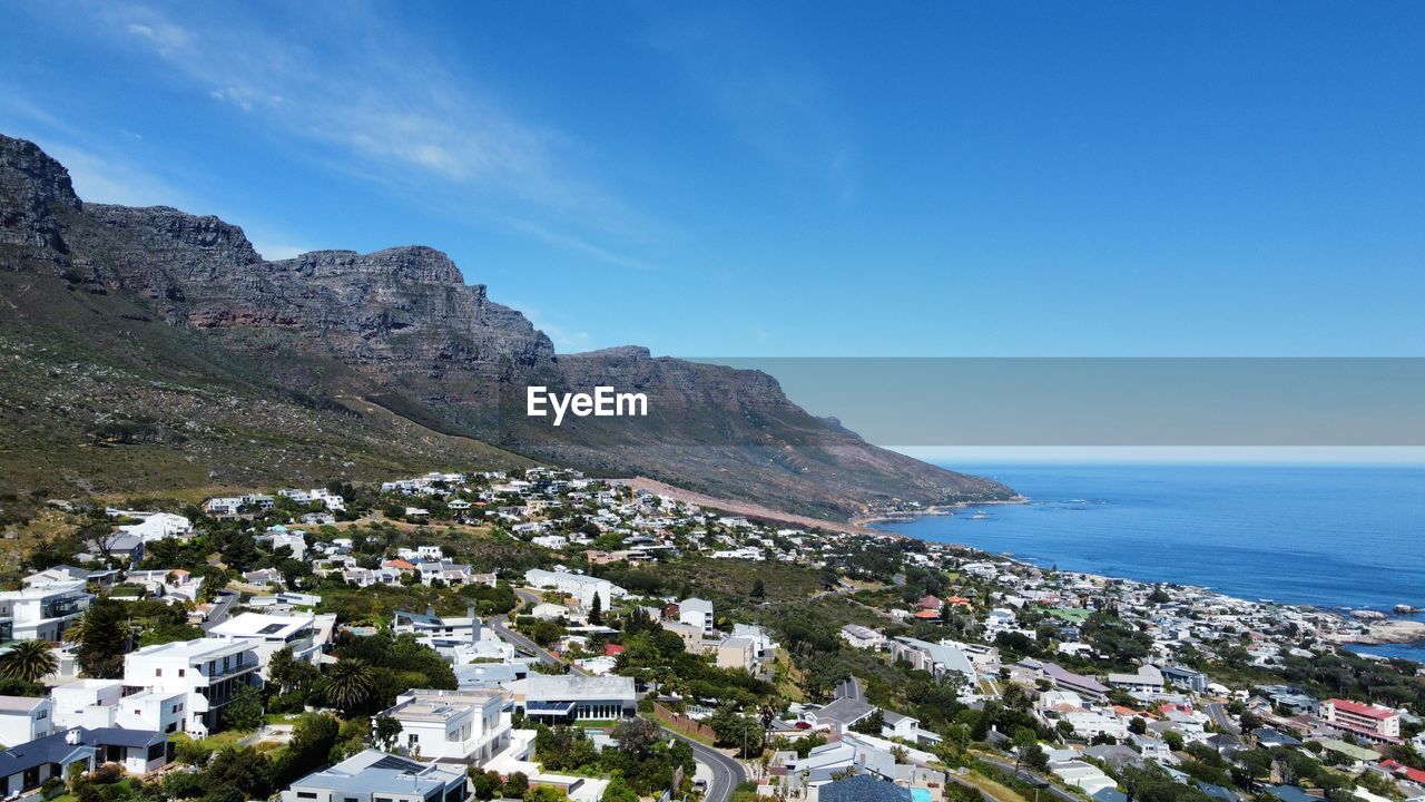 high angle view of townscape by sea against clear blue sky