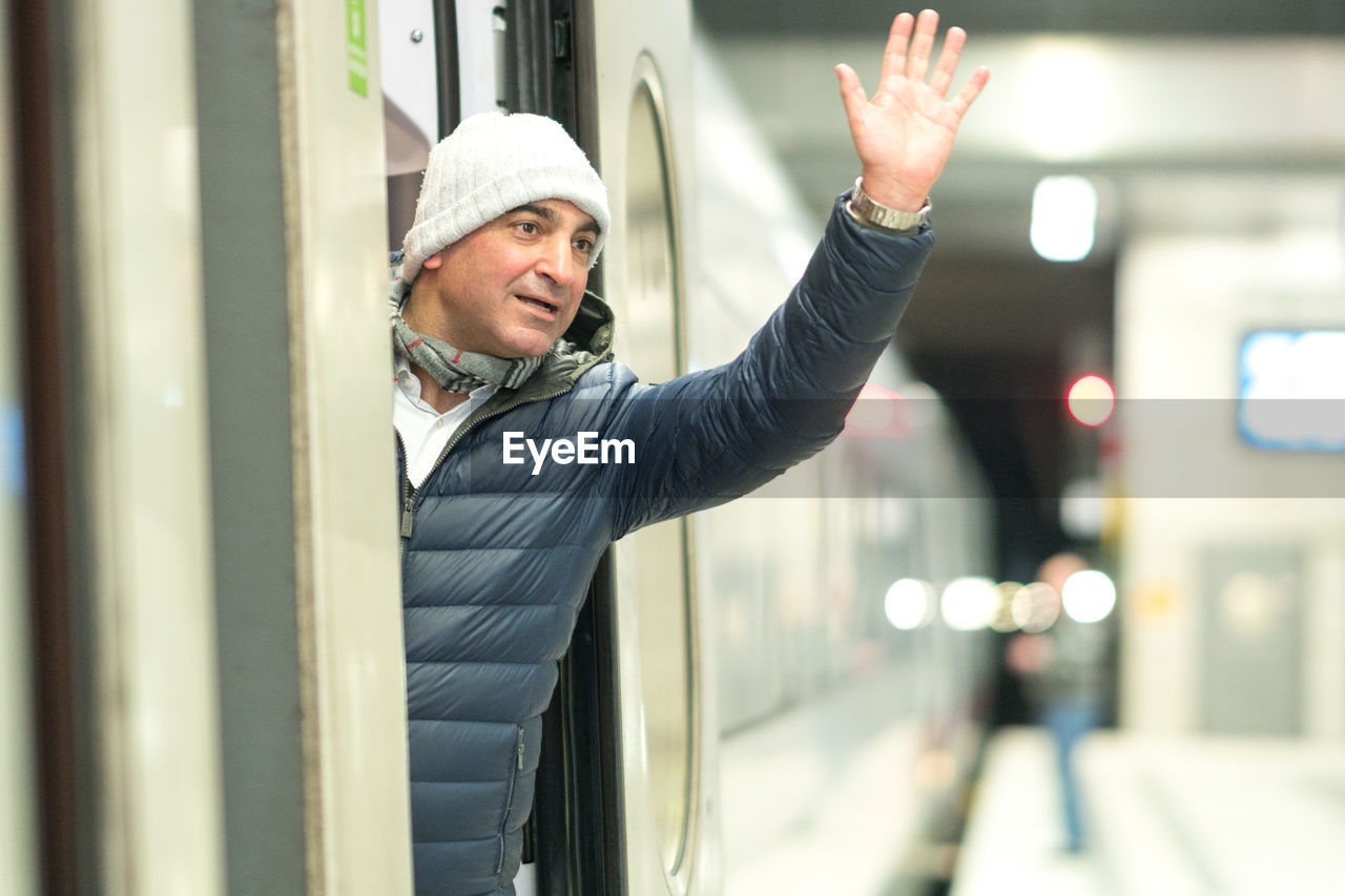Man waving hand while standing in train