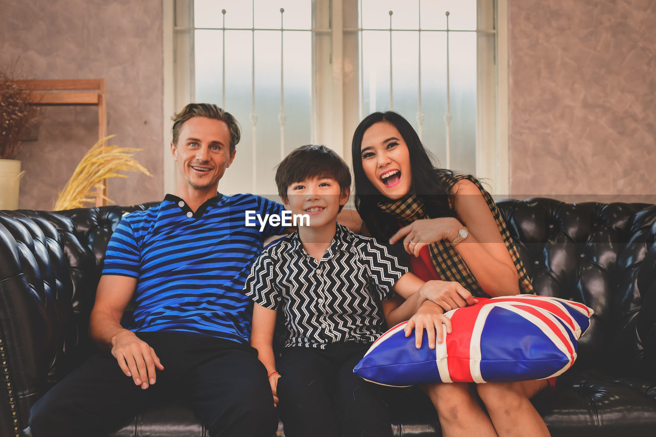 Portrait of happy family sitting on sofa at home