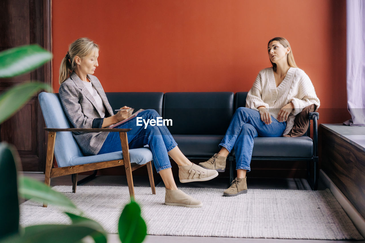 A psychotherapist during a visit  listens and counseling a young woman talking about problems.