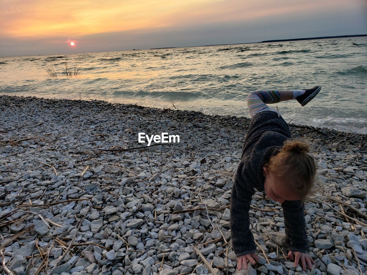 Full length of girl on beach against sky during sunset